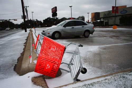 Image of an over-turned red shopping cart in a parking lot.