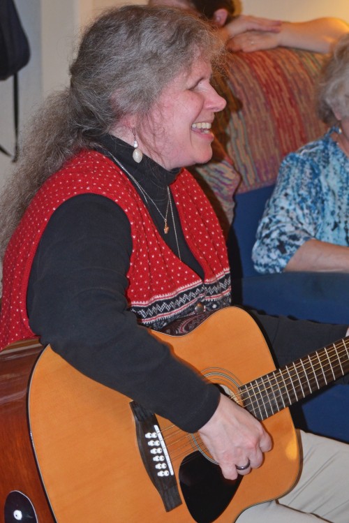 Photo of Anna Dresner seated, playing the guitar