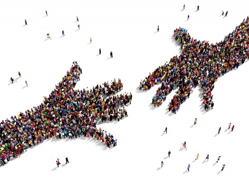 Two hands reaching out toward the other. The hands are made up of a large group of people standing in the shape of the hands.